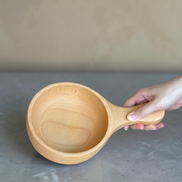Ecohub NZ Entertainers Beech Handled Snack Bowl (15cm) - natural beech wood - being held by the handle over a grey concrete surface