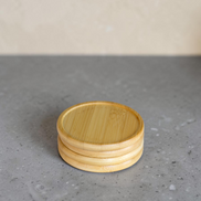 Ecohub NZ Essentials Bamboo Coaster Set of 4 - natural bamboo - stacked neatly on a textured grey concrete surface