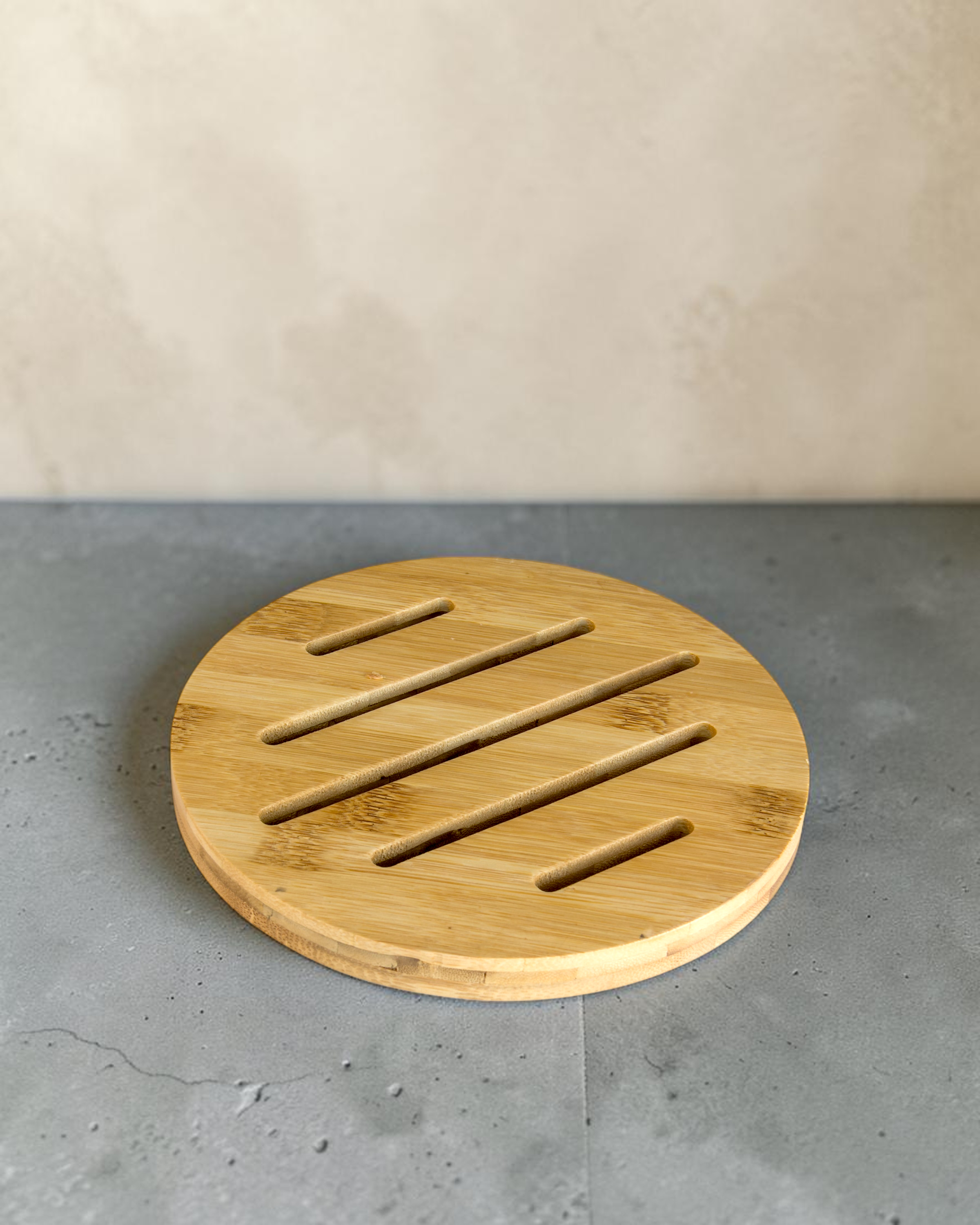 Ecohub NZ Essentials Bamboo Trivet (18cm) - natural bamboo - resting flat on a textured grey concrete surface