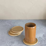 Ecohub NZ Essentials Bamboo Coaster Set of 4 - natural bamboo - one in use under a bamboo cup with others stacked nearby