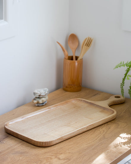 Ecohub NZ Entertainers Ash Serving Paddle Board (50x20cm) - natural ash wood - empty on a sunlit wooden kitchen counter
