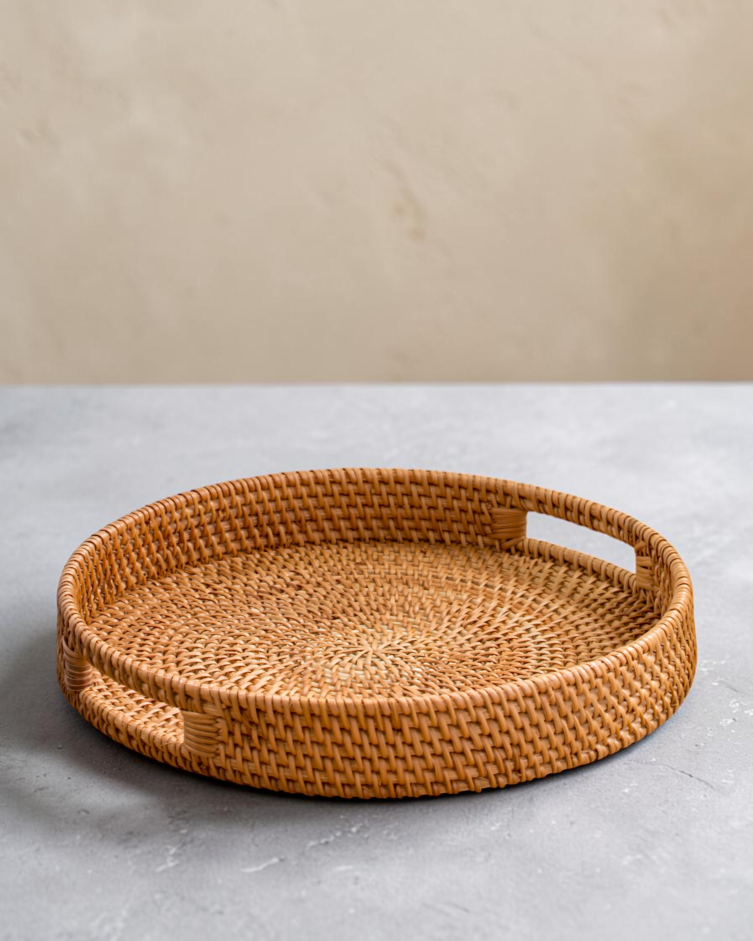 Ecohub NZ Artisans Rattan Round Serving Tray (35cm) - natural rattan - empty on a grey concrete surface