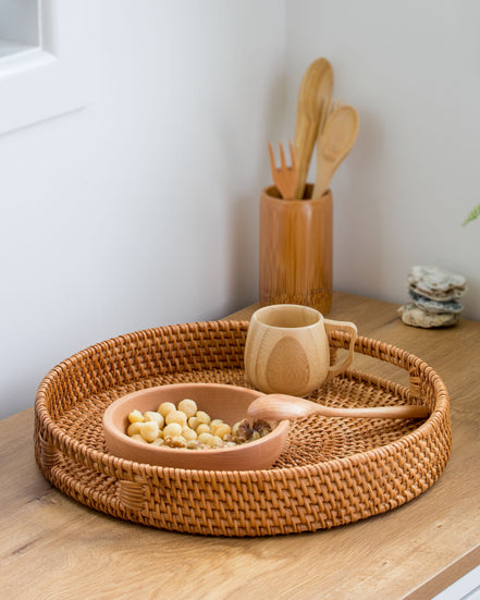 Ecohub NZ Artisans Rattan Round Serving Tray (35cm) - natural rattan - holding a snack bowl and mug on a wood counter