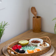 Ecohub NZ Artisans Rattan & Pearl Inlay Oval Serving Tray (31cm) - rattan and pearl - holding food on a wood counter